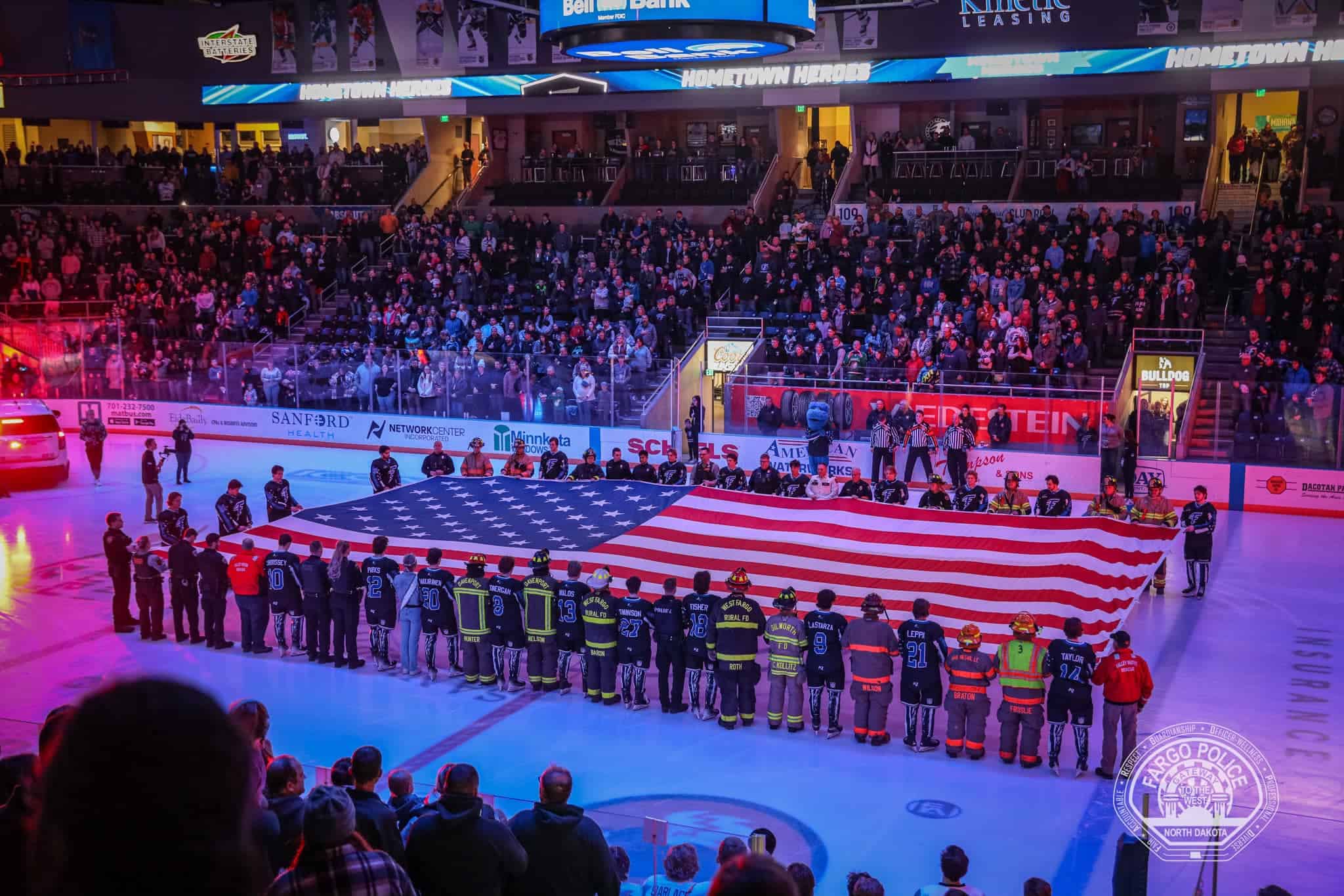 Fargo Force holding US flag on ice at Hometown Heroes night