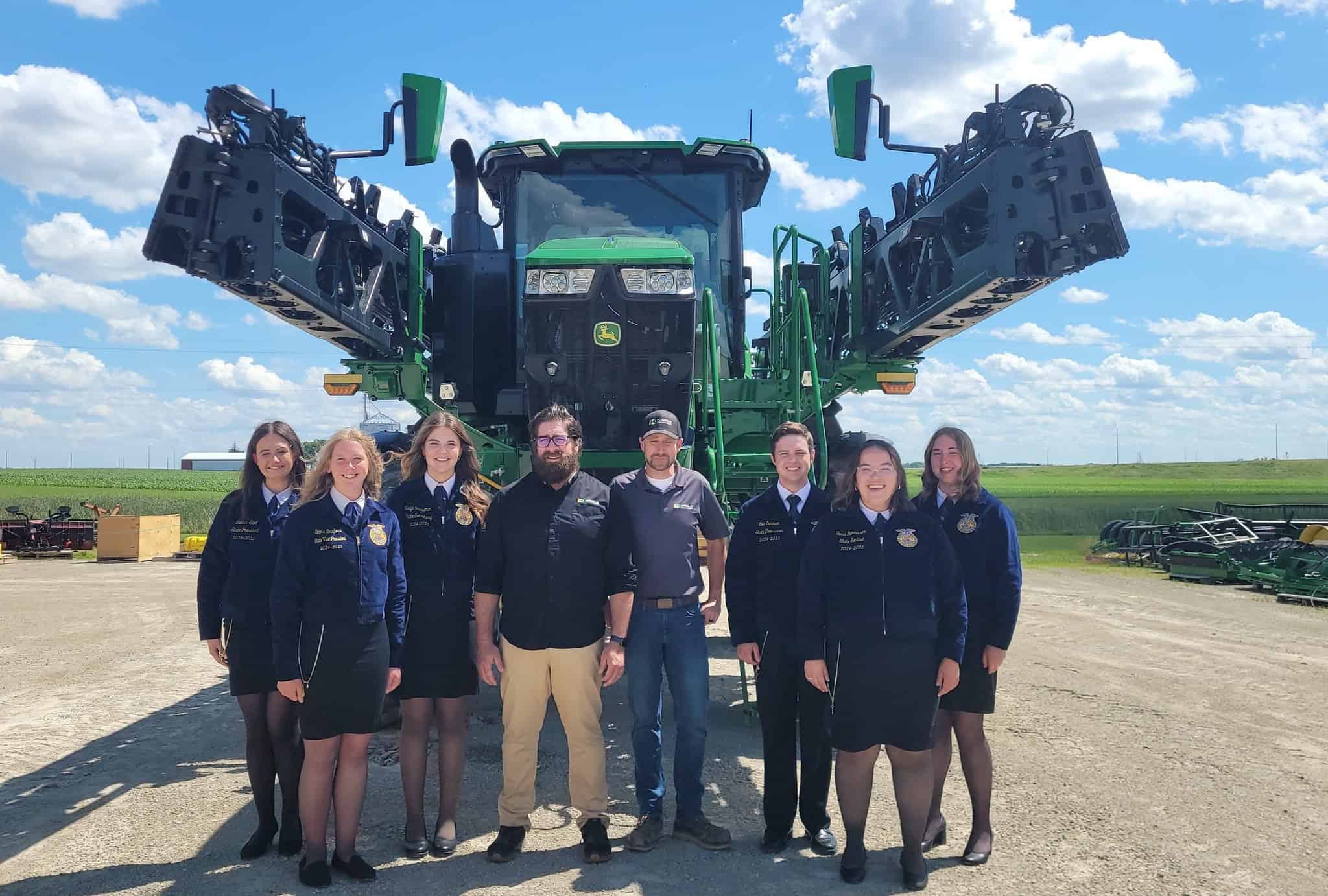 Minnesota FFA Foundation State Officers standing in front of Kibble Equipment John Deere tractor and implement.