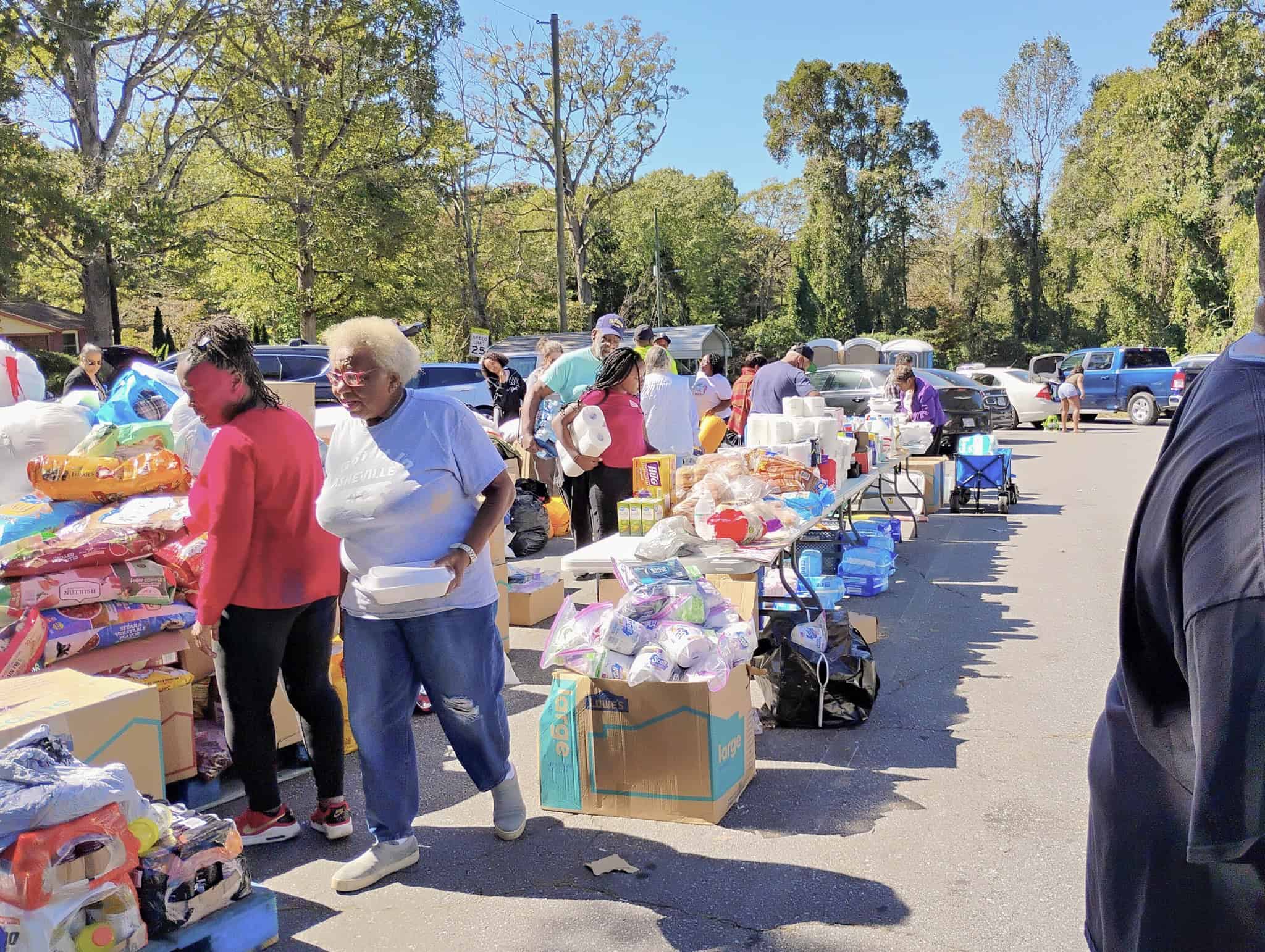 outdoor tables filled with supplies and people gathering what they need