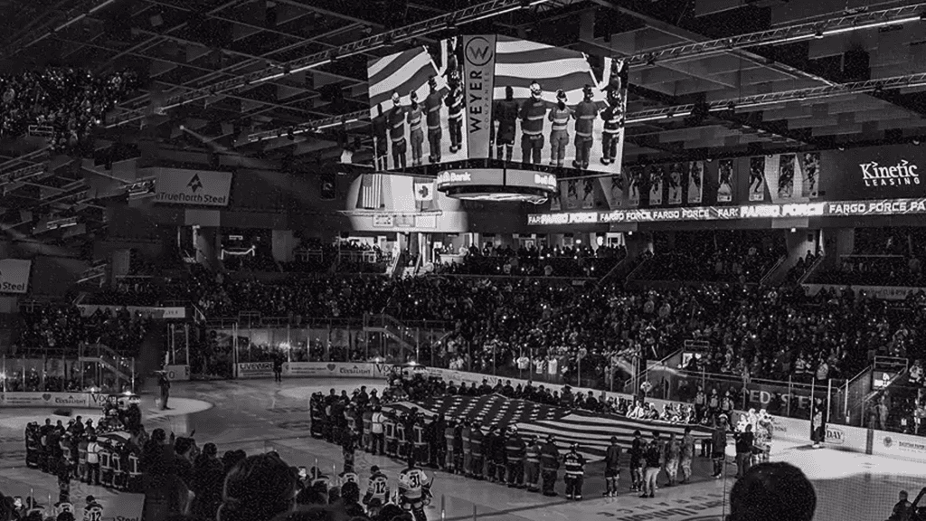 Hometown Heroes night • first responders and Fargo Force player on the ice rink hold the US flag